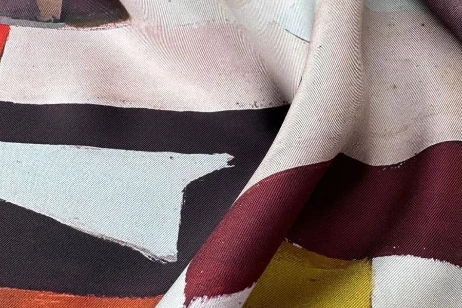 Close view of a silk twill scarf printed with an abstract painting in pale blue, burgundy and black