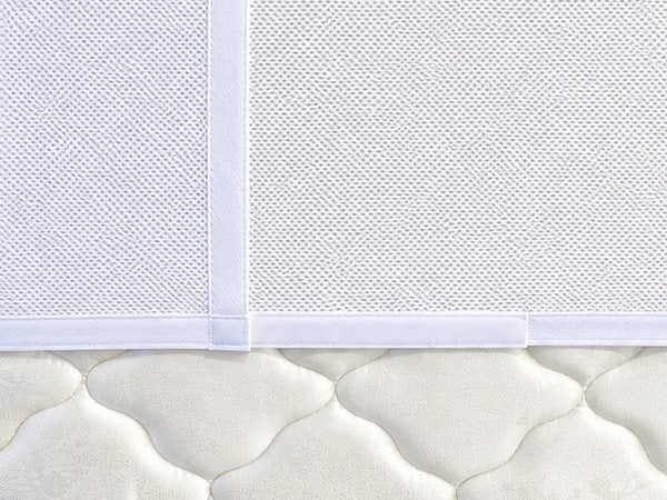 Close-up of the overlapping mesh flap and its hook-and-loop strip underneath the mattress