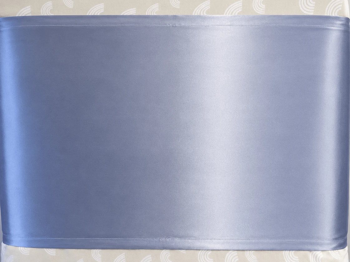 Close-up of the Sky Blue silk panel fitted across a cot mattress, with the fitted sheet visible above it